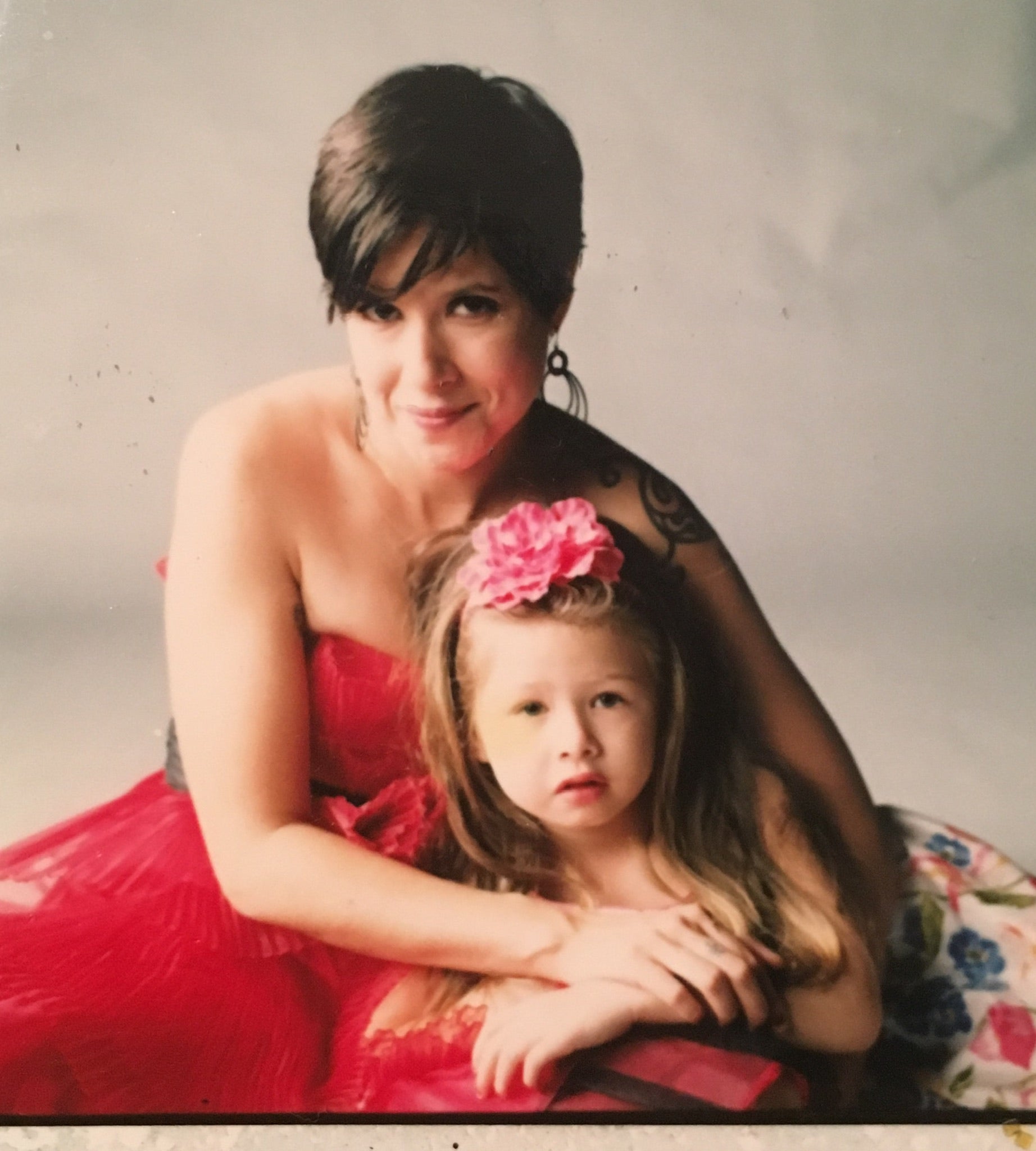 Sandra Velazquez and her daughter posing together in a warm family portrait with pink tones.