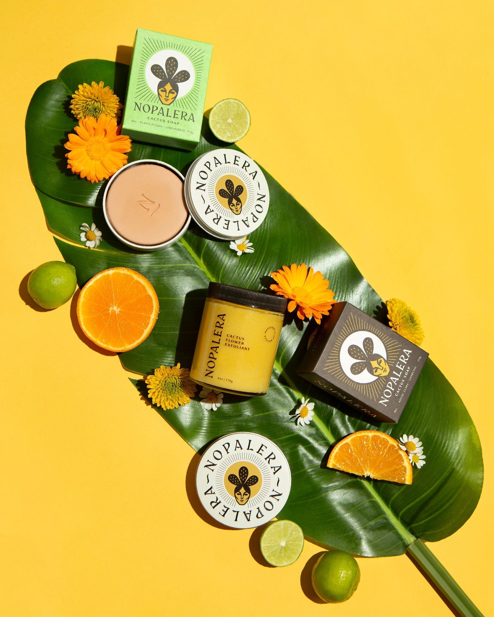 Nopalera body care collection styled with citrus and tropical botanicals on a vibrant yellow background.