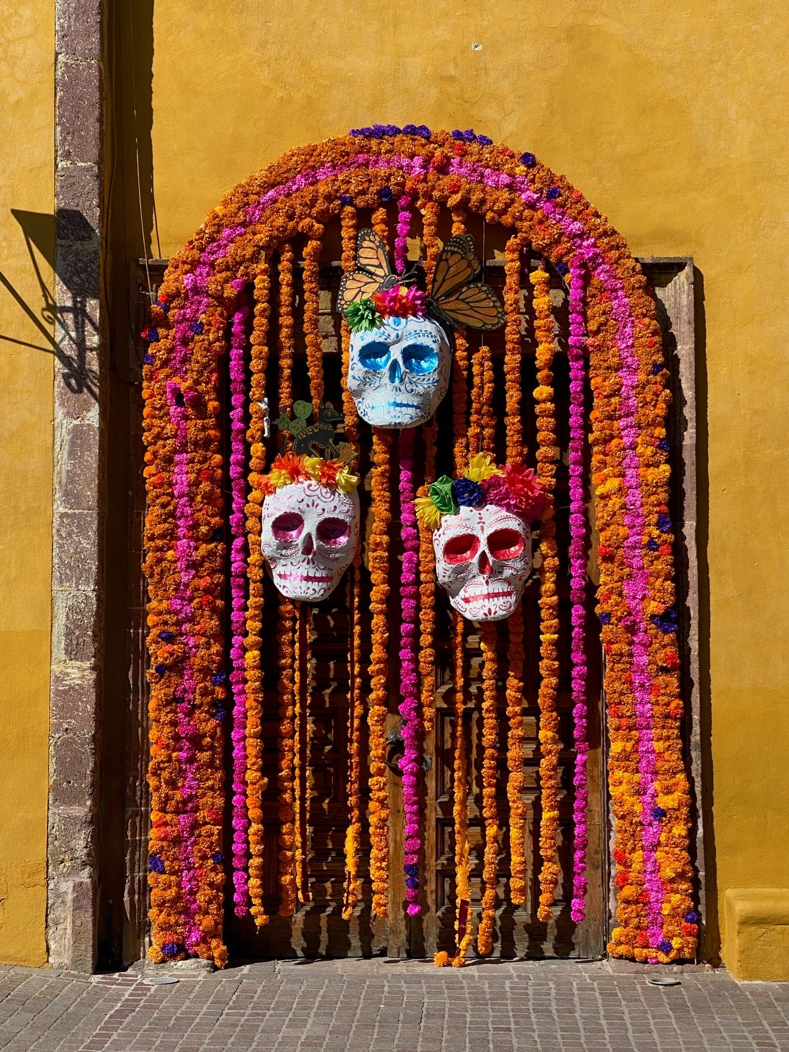 Colorful Día de los Muertos display with floral garlands and decorative skull masks.