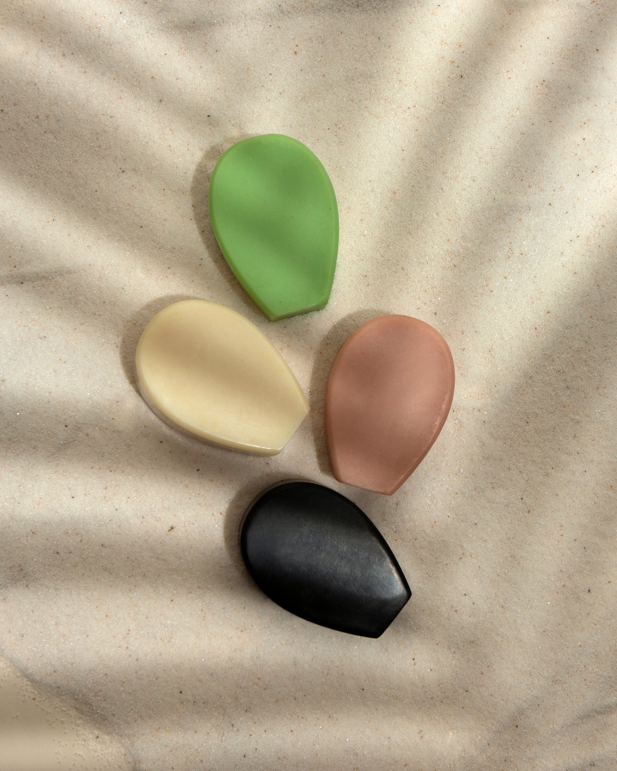 Colorful Nopalera beauty bars arranged on textured sand.