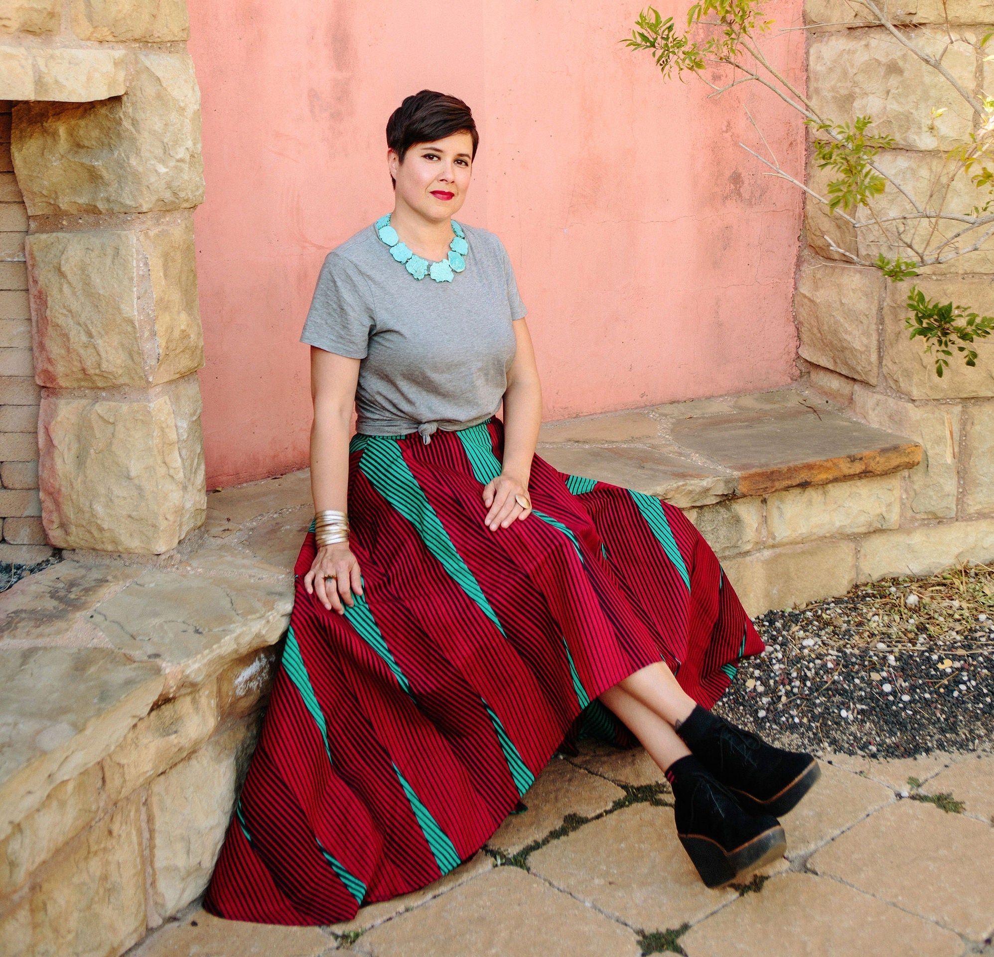 Sandra Velazquez seated outdoors wearing a colorful traditional-inspired skirt in a lifestyle portrait.