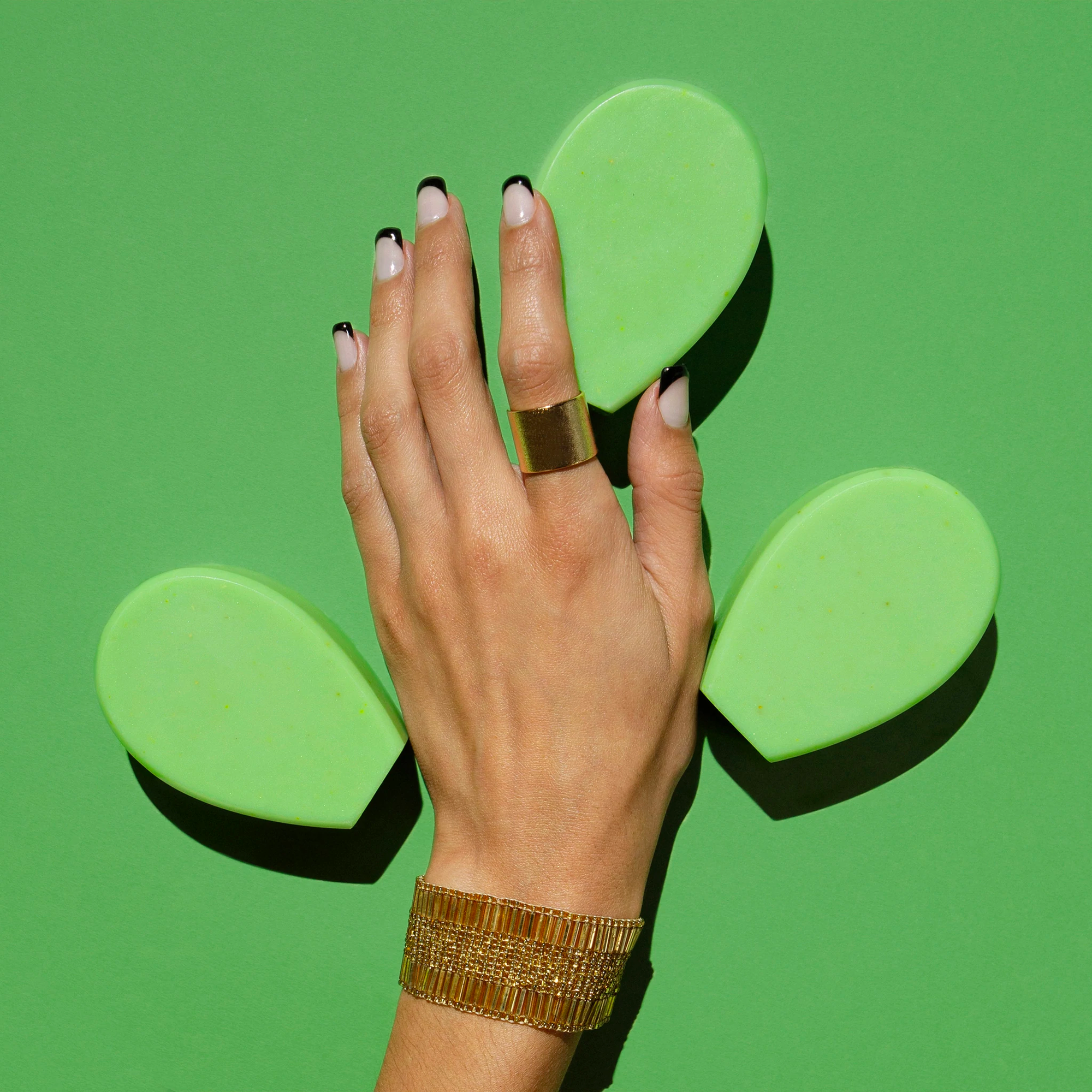 Hand holding Nopalera beauty bars against a vibrant green background.
