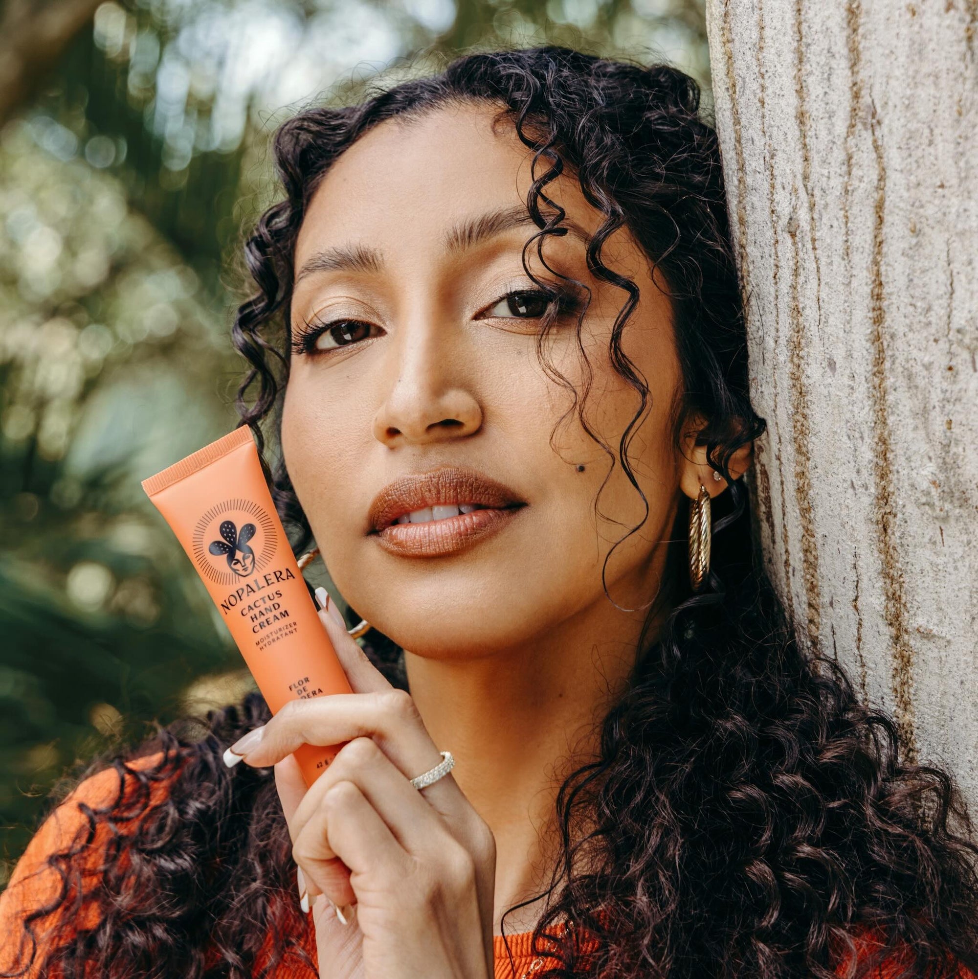 Woman holding a tube of Nopalera  Flor de Madera hand cream in a natural setting