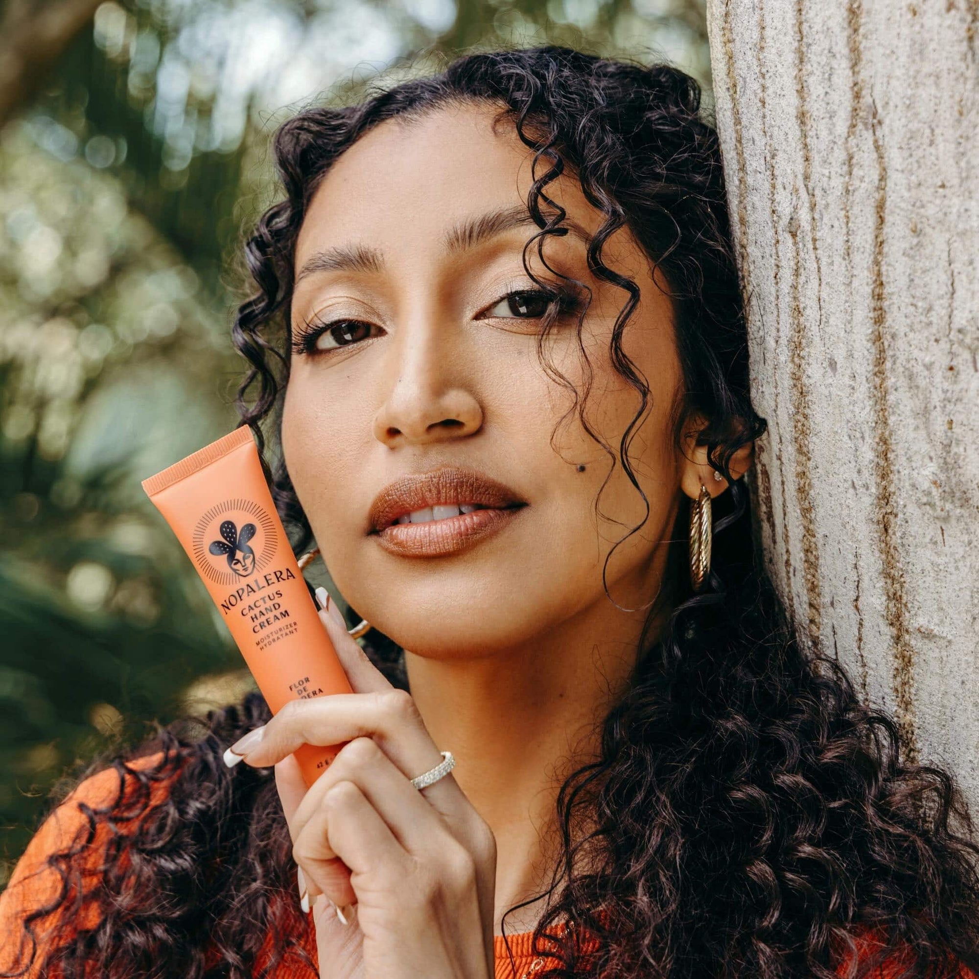 Woman holding Nopalera Flor de Madera cactus hand cream in a natural setting