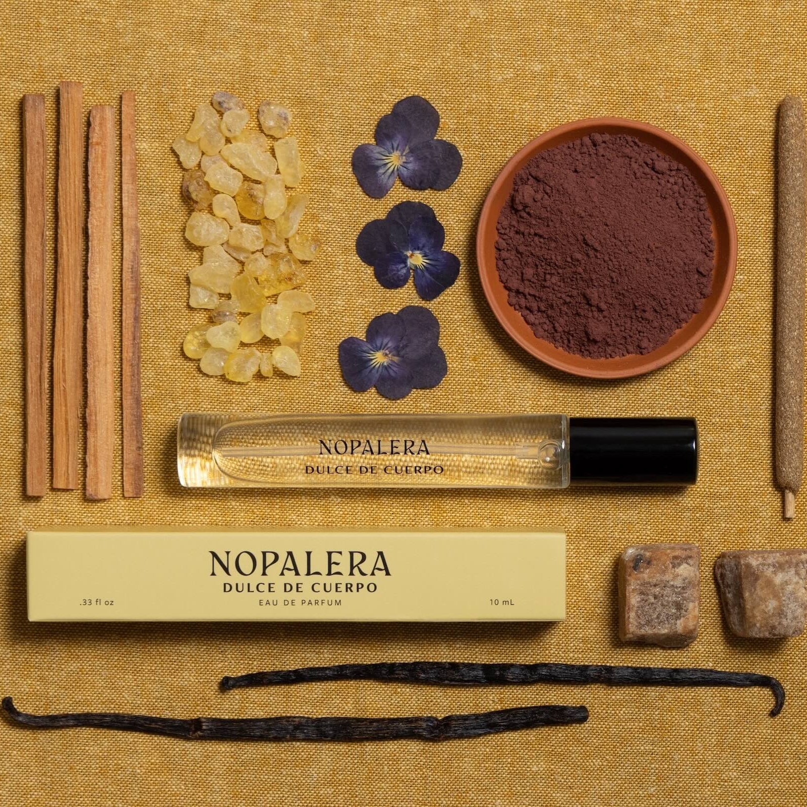 Nopalera Luxury Mexican fragrance travel spray perfume  dulce de cuerpo bottle with ingredients on a textured surface