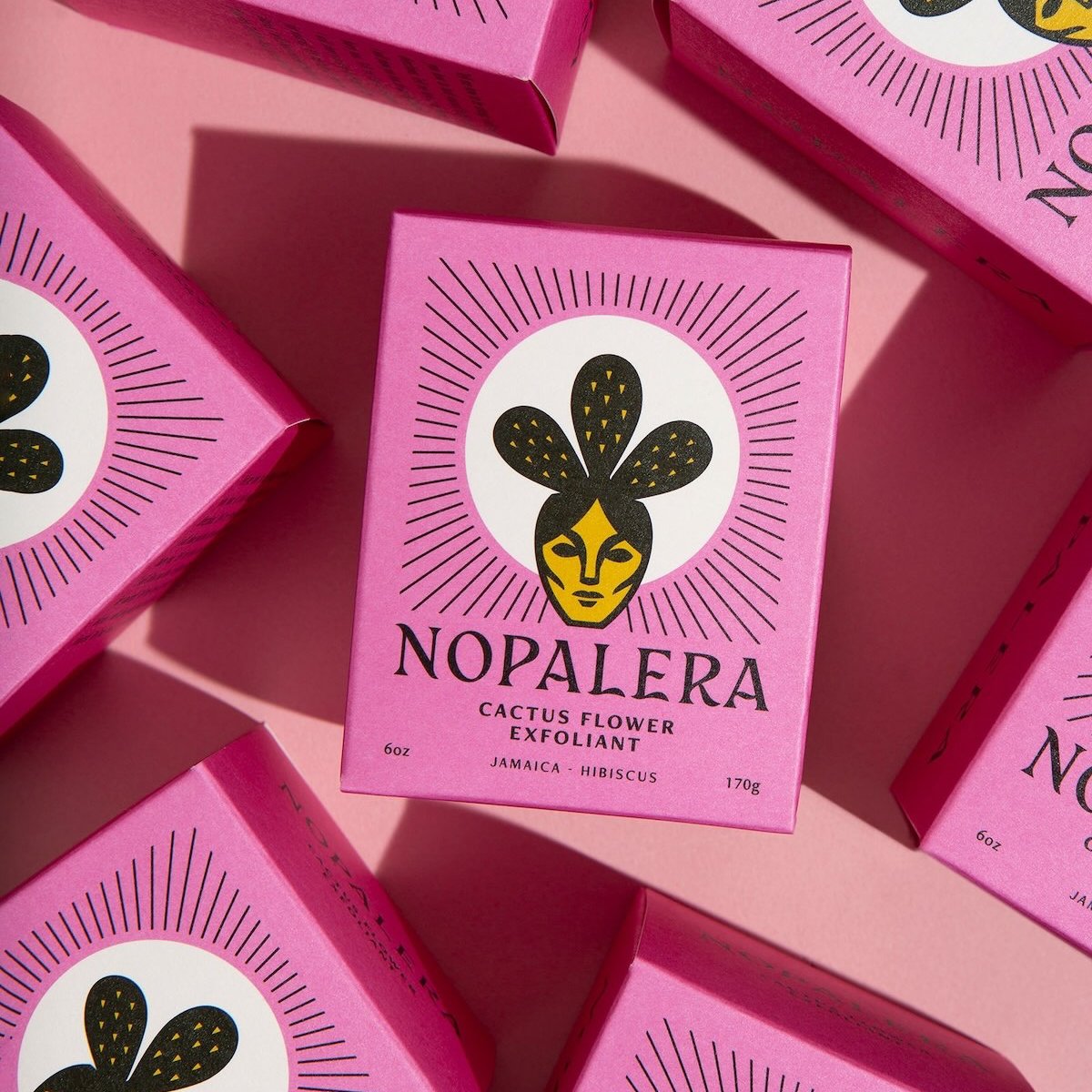 Nopalera Cactus Flower Exfoliant Hibiscus box surrounded by vibrant purple packaging.