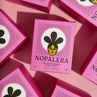 Nopalera Cactus Flower Exfoliant Hibiscus box surrounded by vibrant purple packaging.