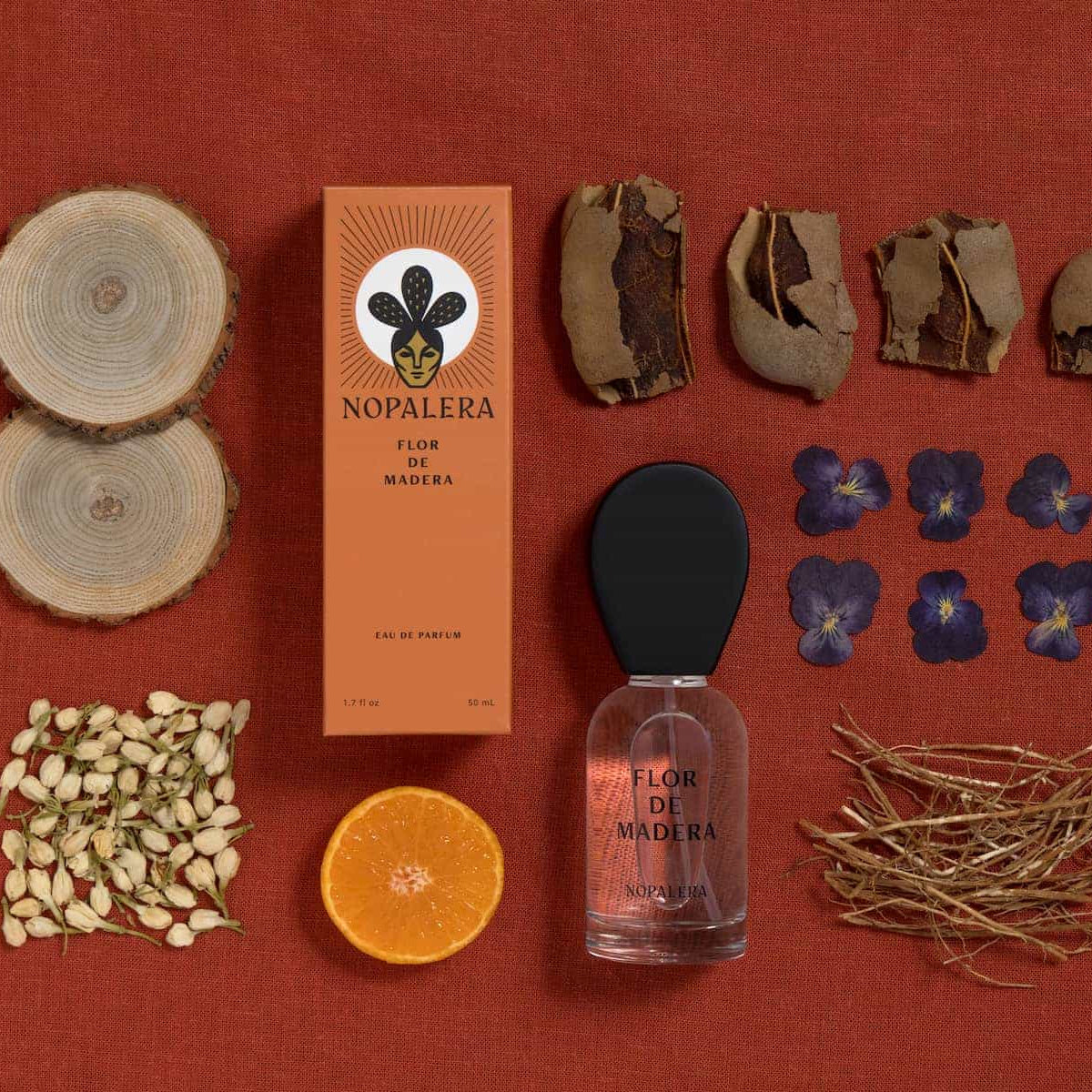 Nopalera Flor de Madera perfume set with natural elements on a red background