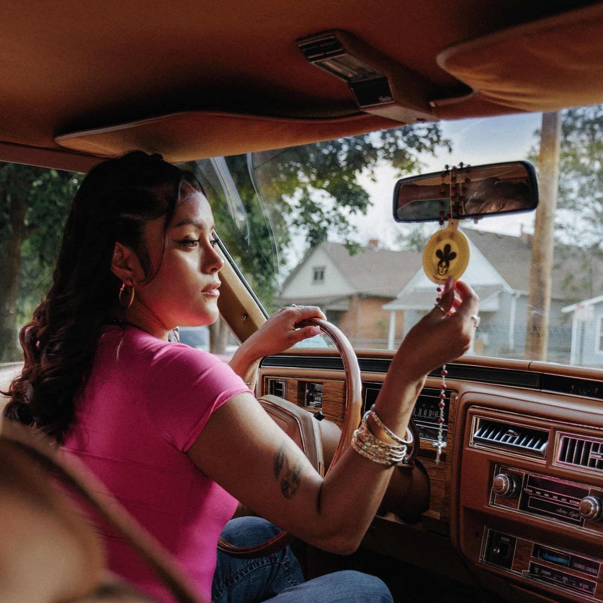 Driver hanging a Buena Vibra car freshener from a rearview mirror