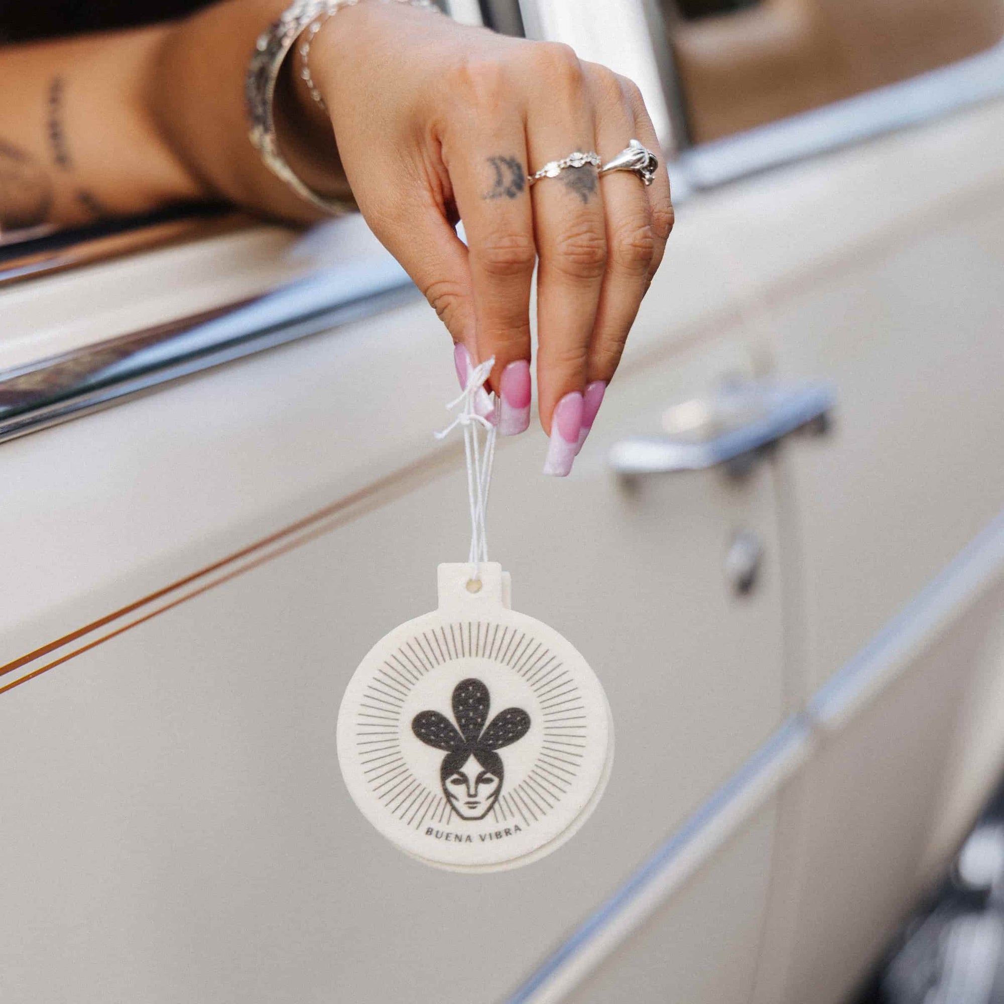 Buena Vibra car freshener held beside a vintage car