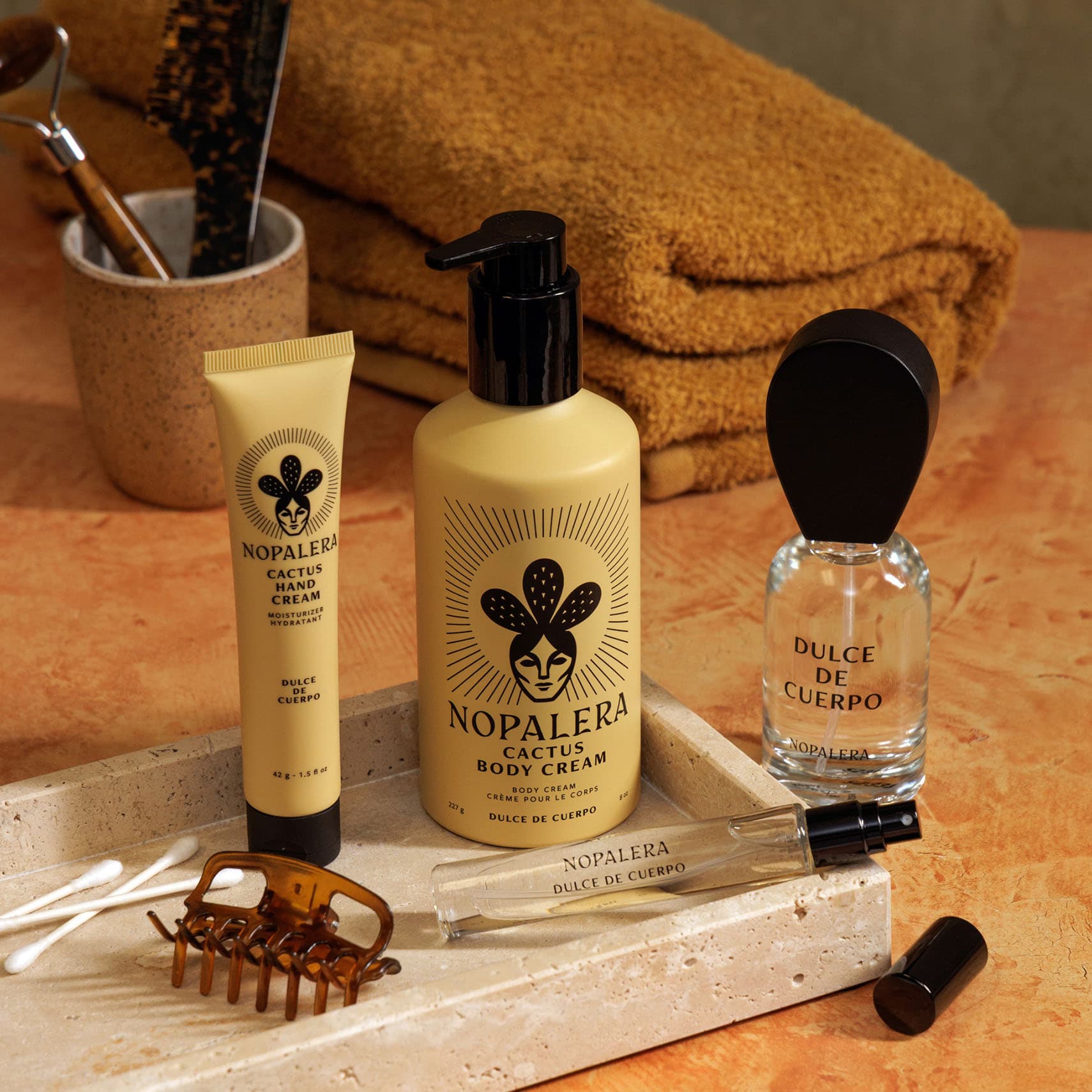 Nopalera Dulce de Cuerpo skincare products on a wooden tray with towels in the background