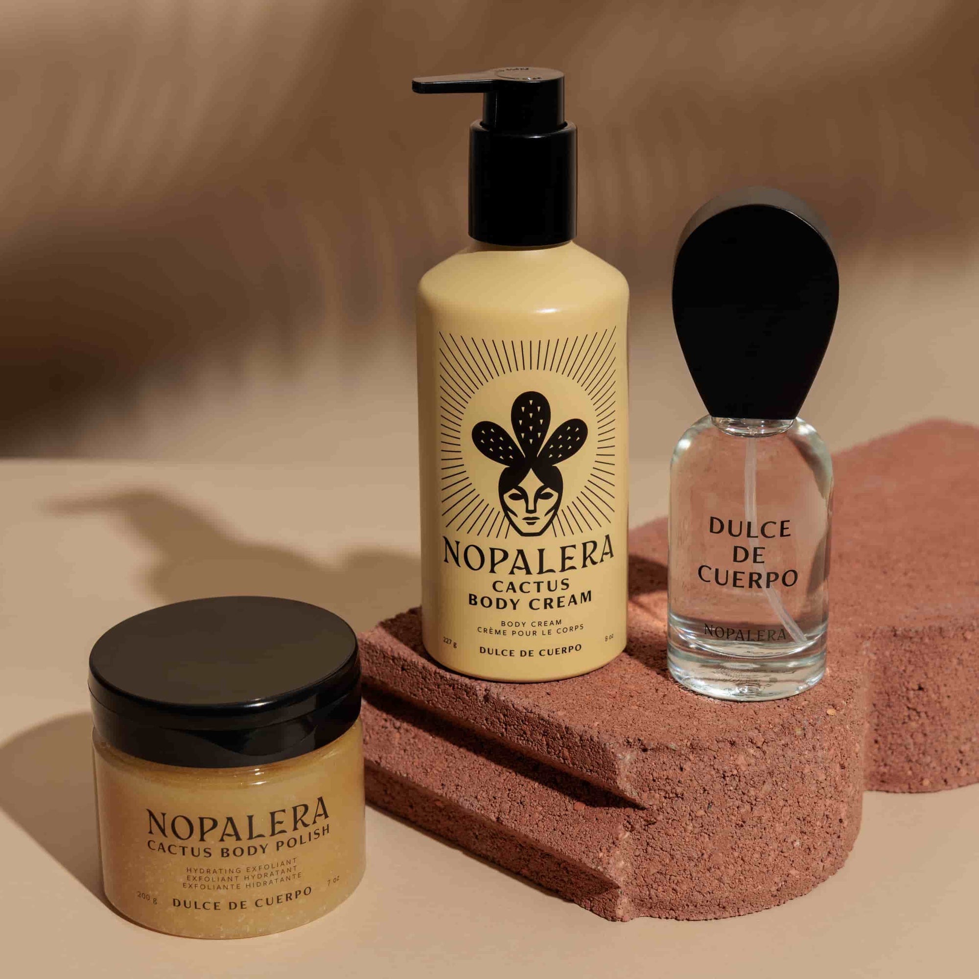 Nopalera Dulce de Cuerpo skincare products including cream, polish, and perfume on a textured surface with a warm background.
