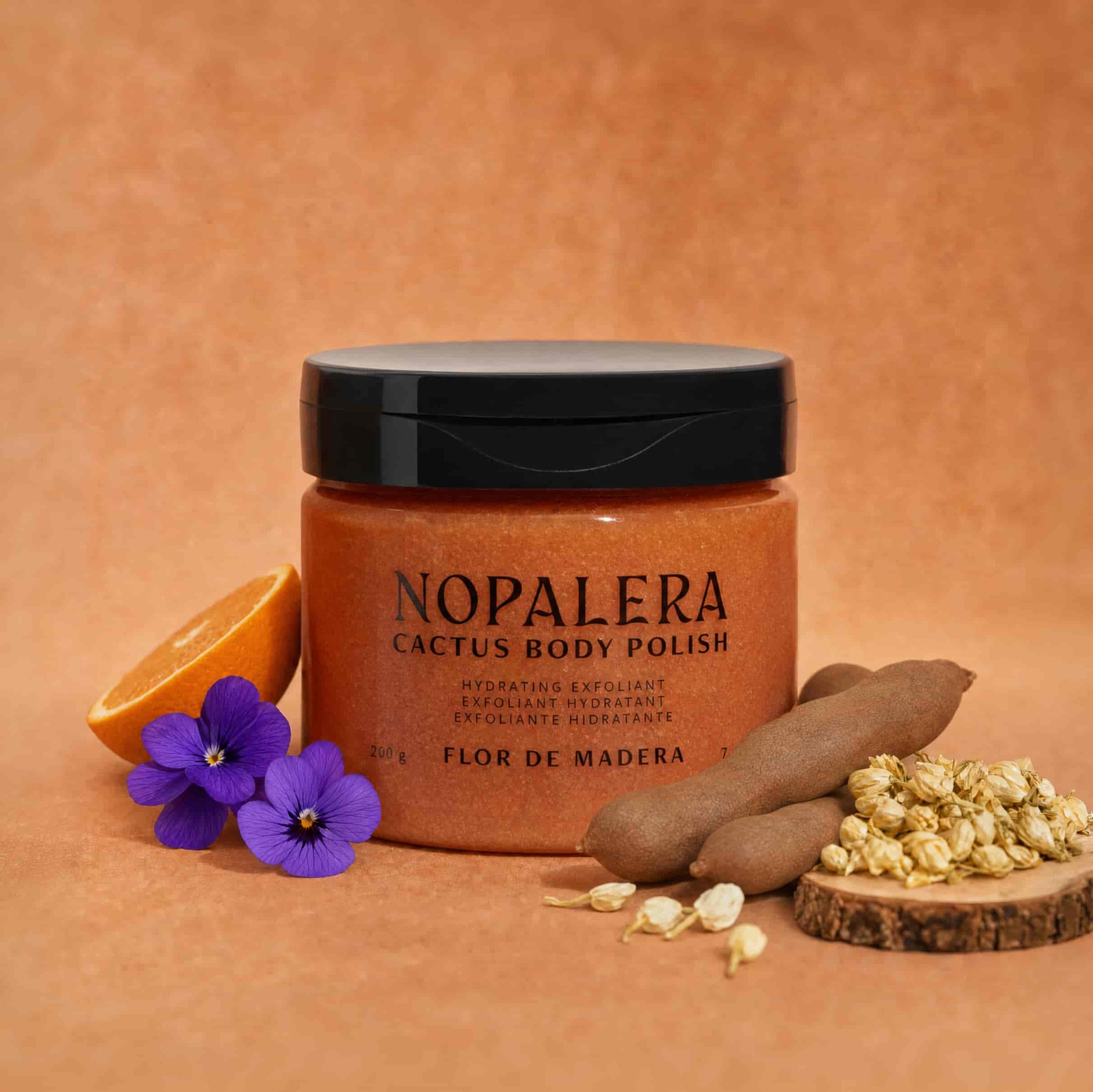 Jar of Nopalera Cactus Body Polish Flor de Madera on a brown background with cactus and flowers.