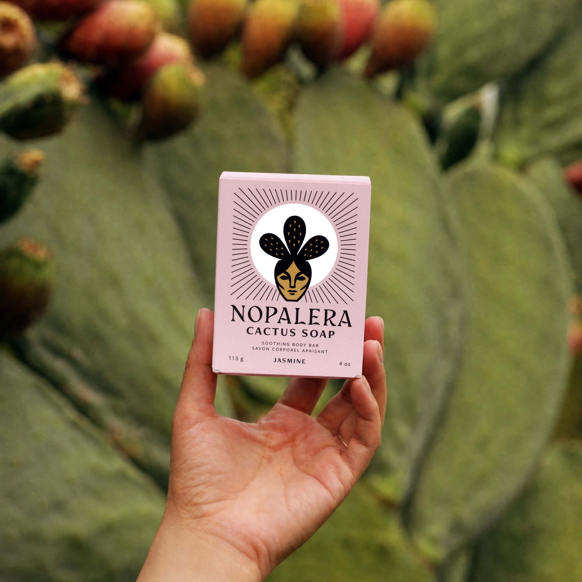 A hand holding a Nopalera Jasmine Soap with a cactus in the background.