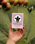 A hand holding a Nopalera Jasmine Soap with a cactus in the background.