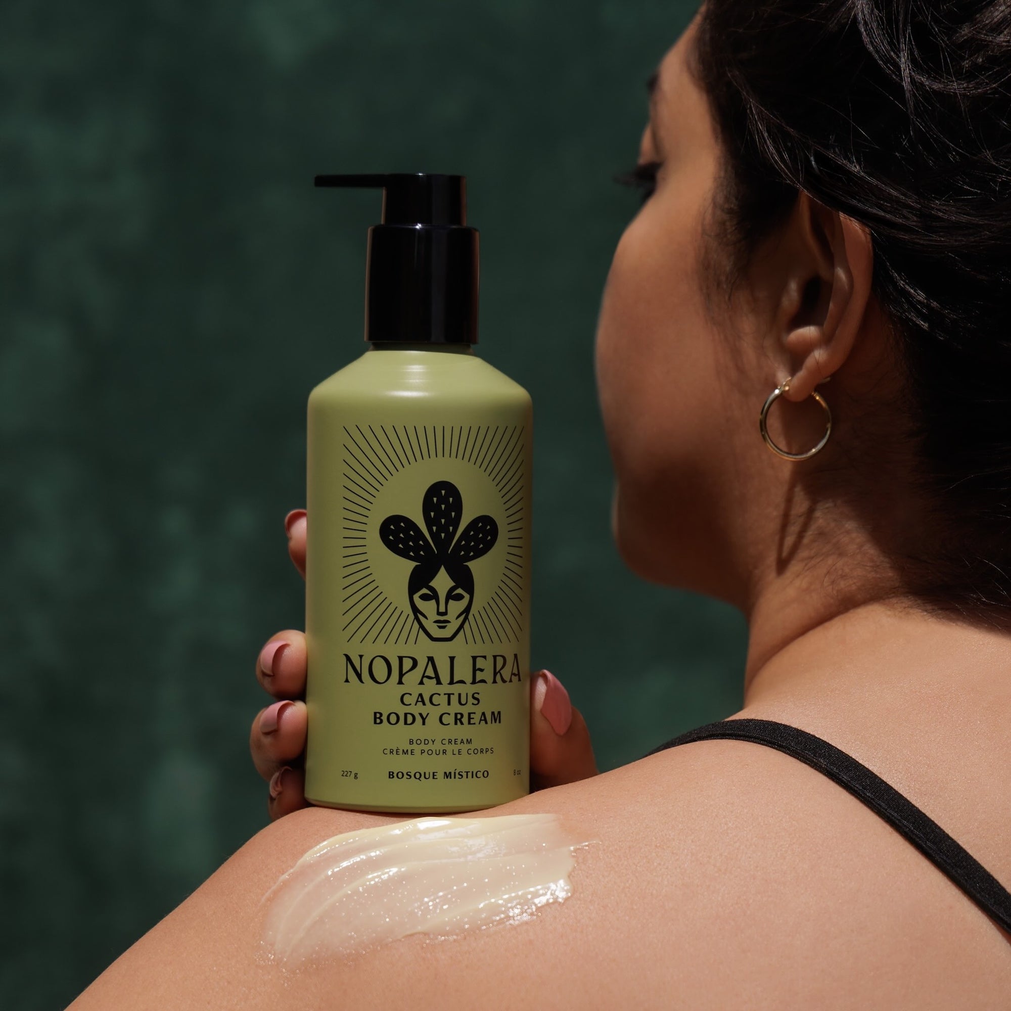Woman applying Nopalera cactus body cream Bosque Místico on shoulder.