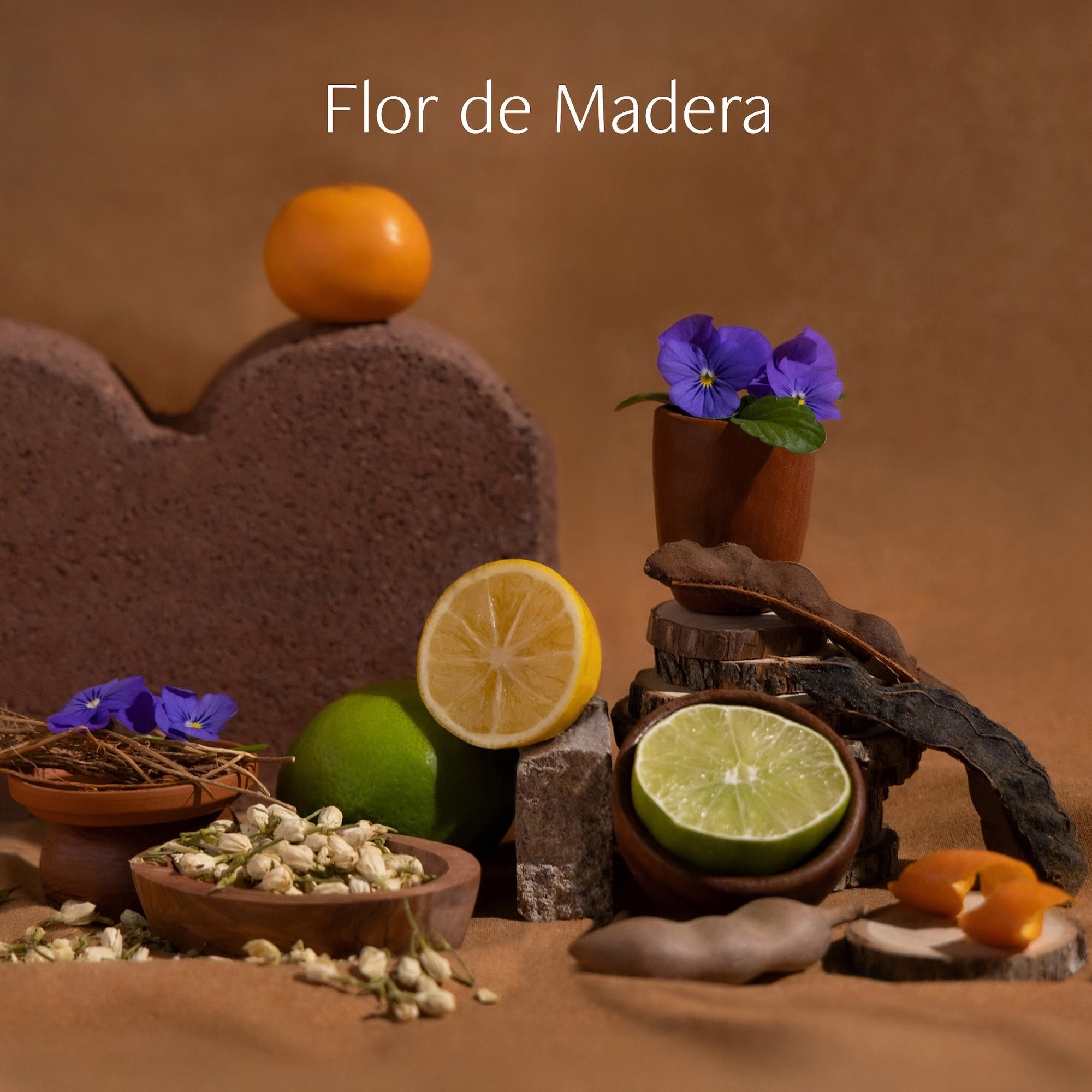 Flor de Madera fragrance ingredients including citrus, flowers, and natural elements arranged in a warm-toned composition