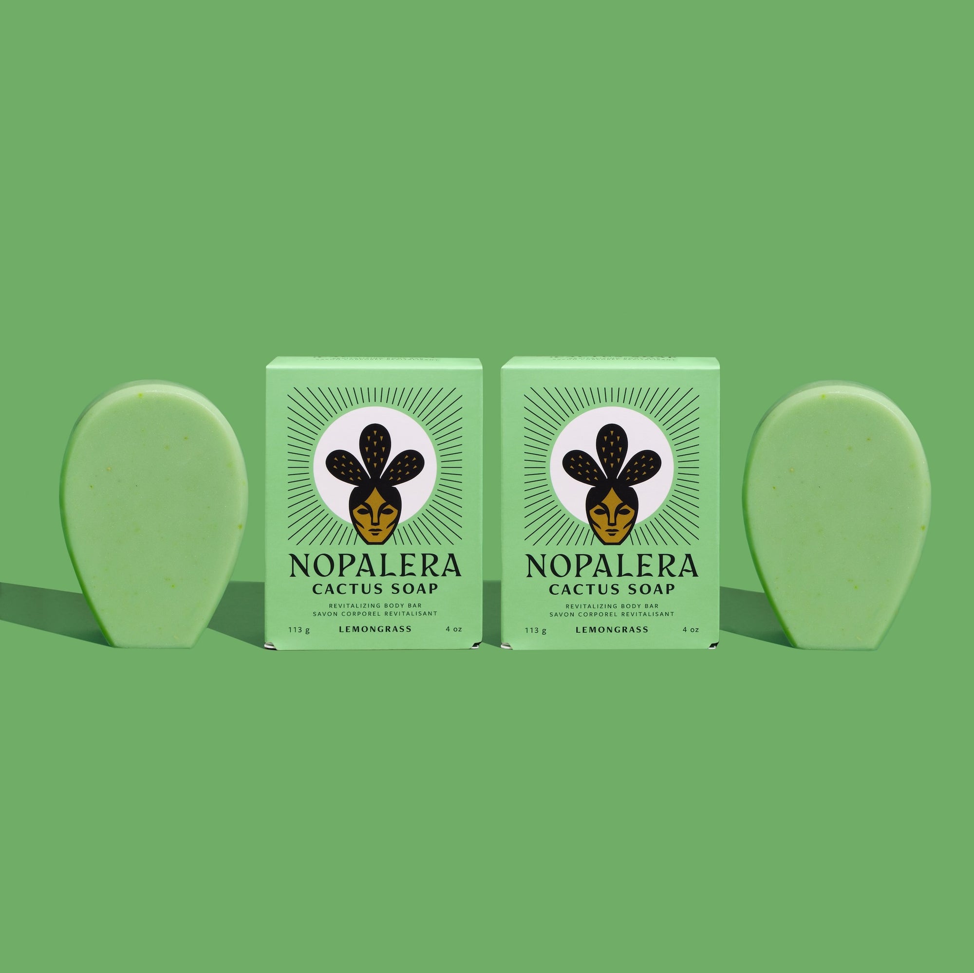 Two bars of lemongrass cactus soap with packaging, green background.