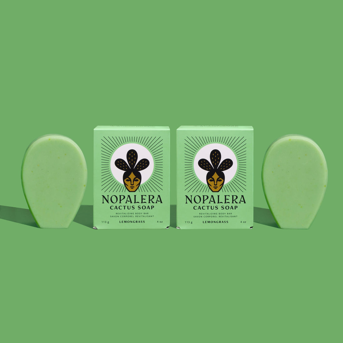Two bars of lemongrass cactus soap with packaging, green background.