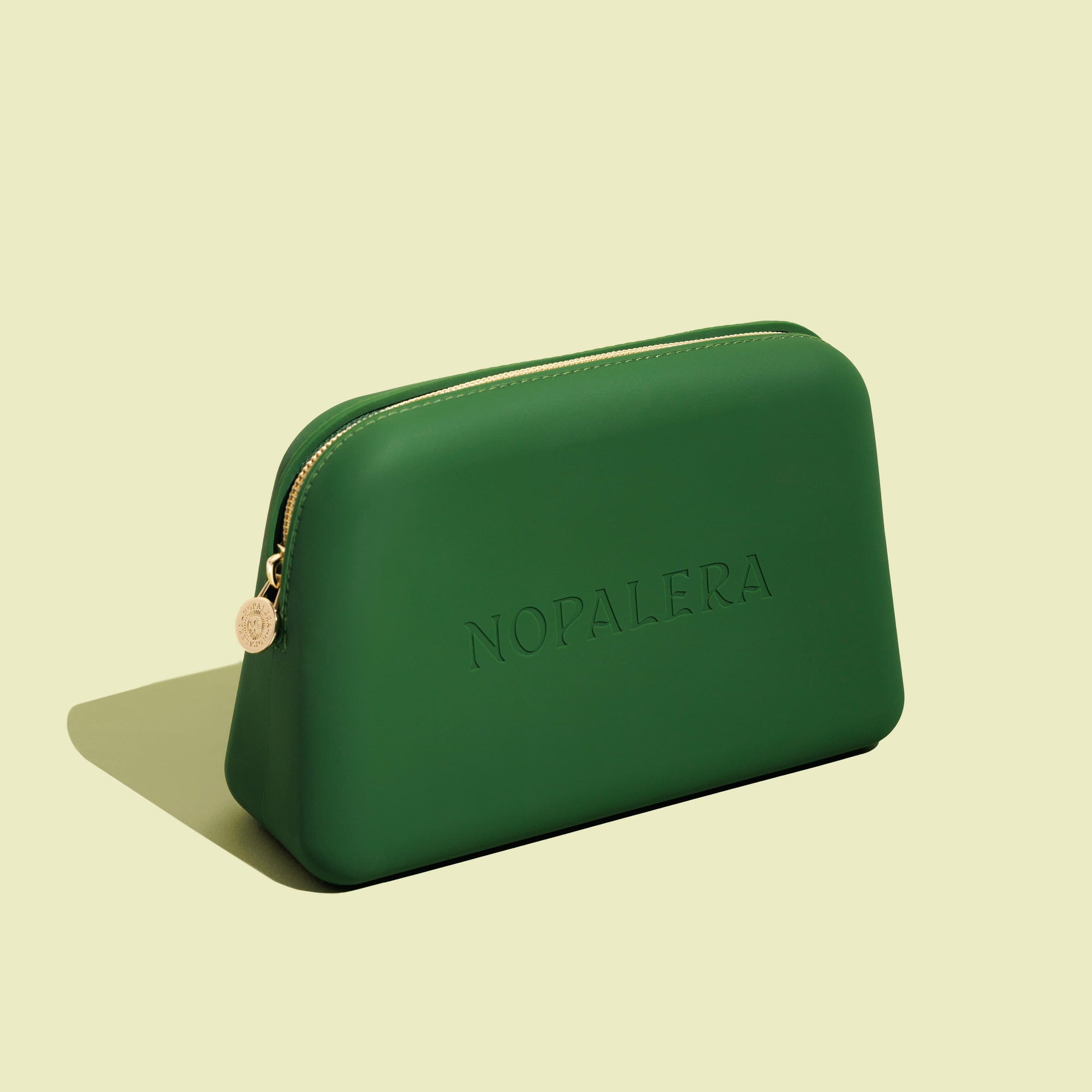 Green nopalera.momsmetic pouch with gold zipper and embossed logo on a neutral background.