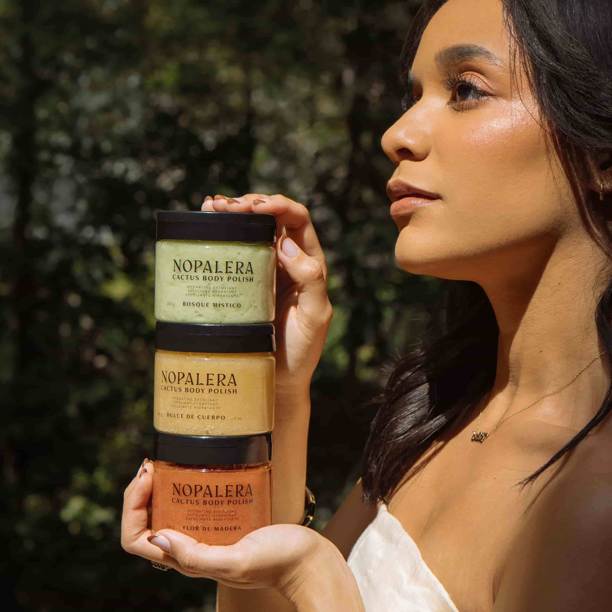 Woman holding Nopalera body polish in a natural setting