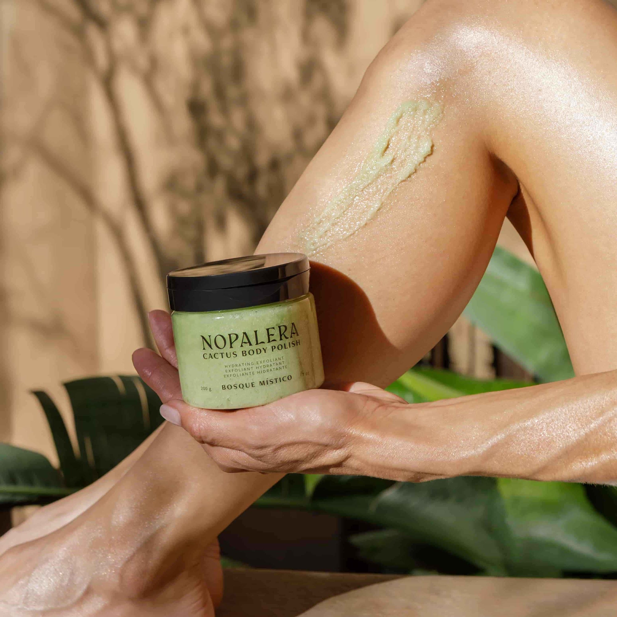 Person applying Nopalera body polish to their leg with a natural background