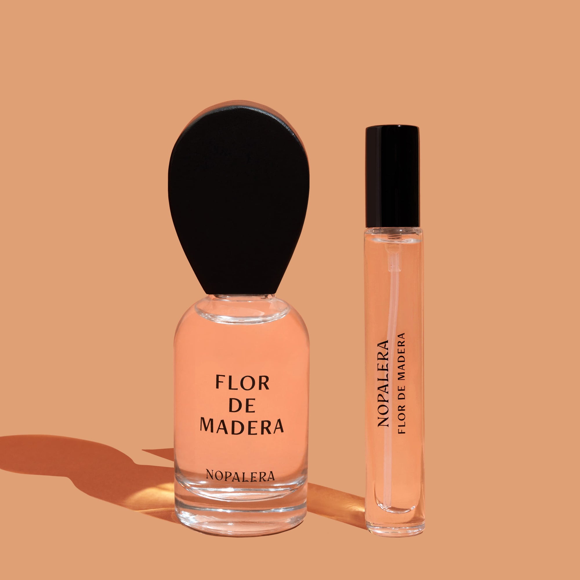 Two bottles of Nopalera Flor de Madera perfume, including a 50 ml full-size and a travel-size bottle, displayed on a beige background.