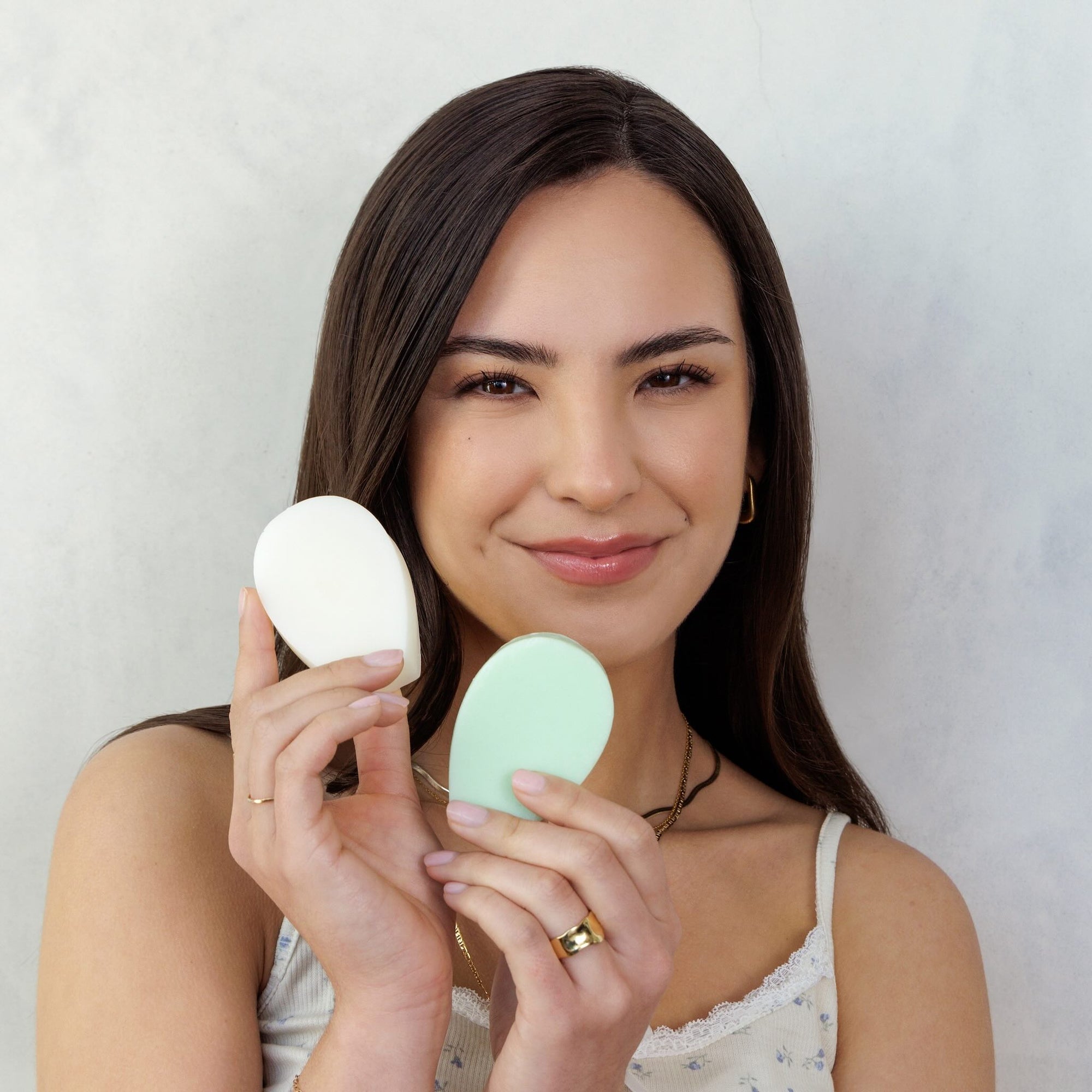 Model holding two Nopalera beauty sahmpoo and conditioner bars against a neutral background