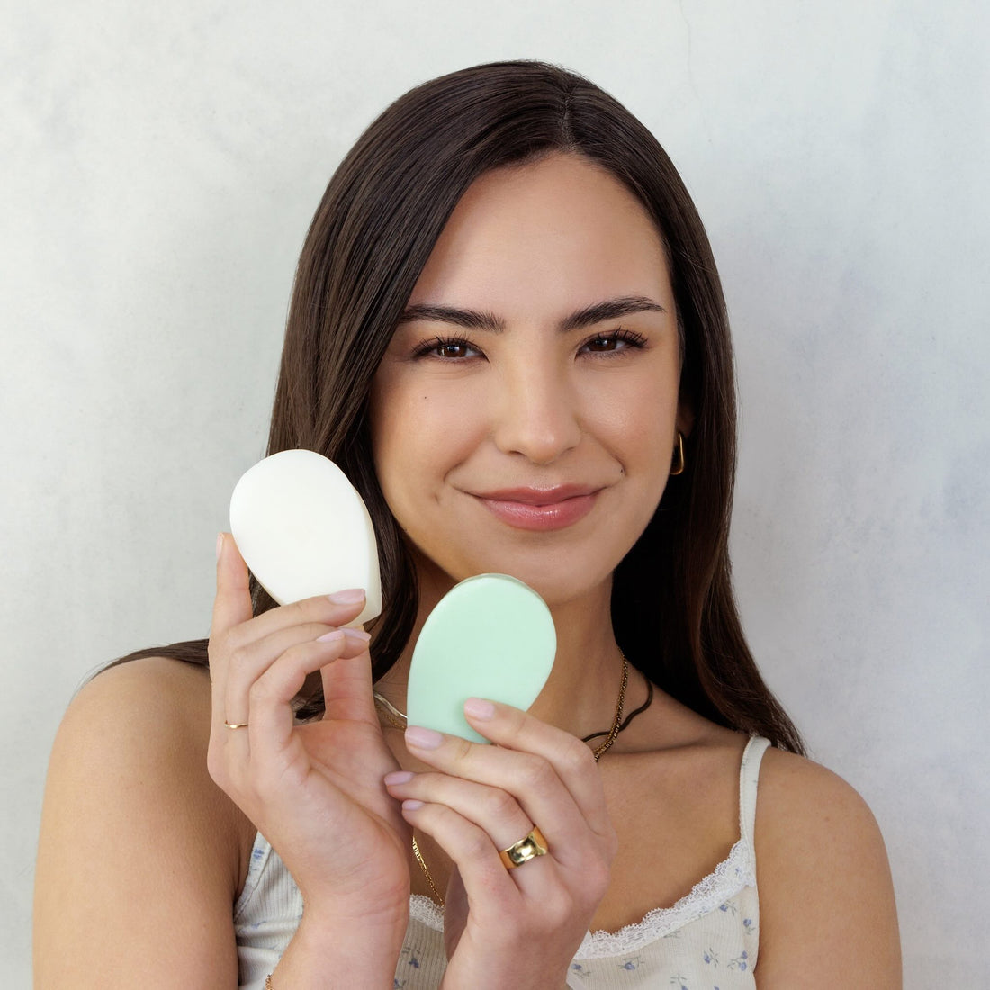 Model holding two Nopalera beauty sahmpoo and conditioner bars against a neutral background