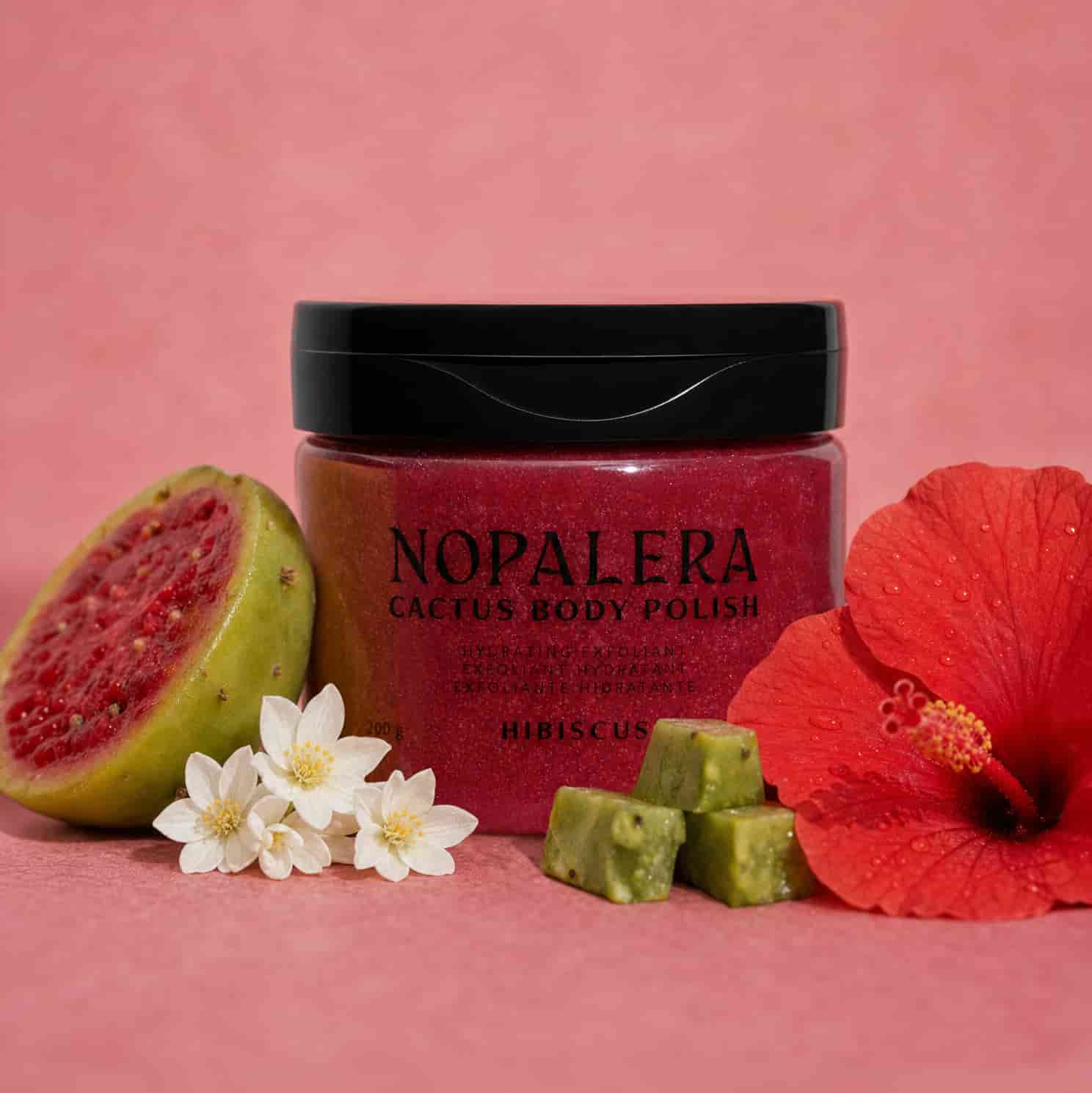 Nopalera cactus body polish jar with guava, flowers, and hibiscus on a pink background