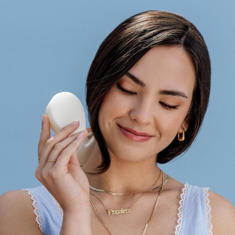 Model holding a Nopalera solid beauty bar against a soft blue background.