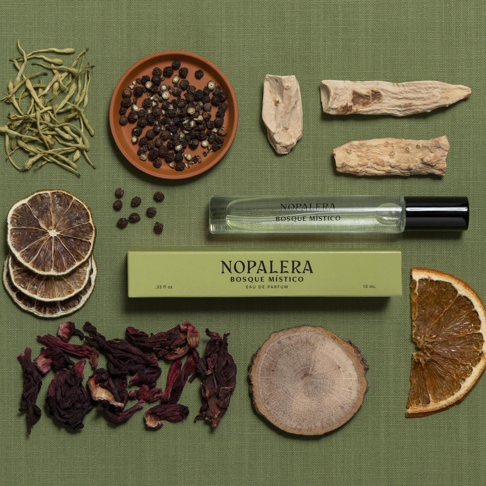 Nopalera Luxury Mexican  travel spray perfume Bosque Místico bottle surrounded by dried herbs and elements on a green background