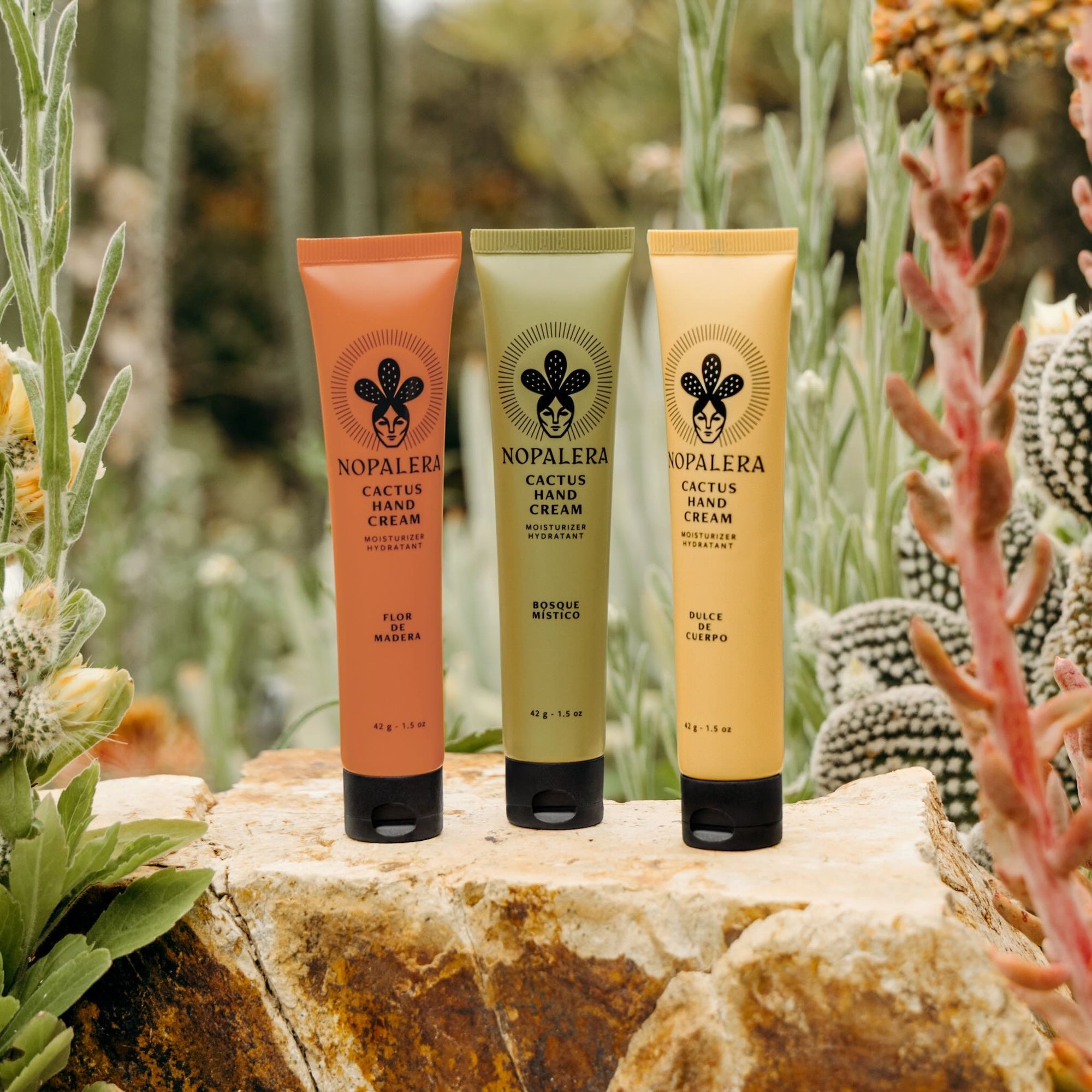 Three tubes of Nopalera cactus hand cream on a rock with a cactus background