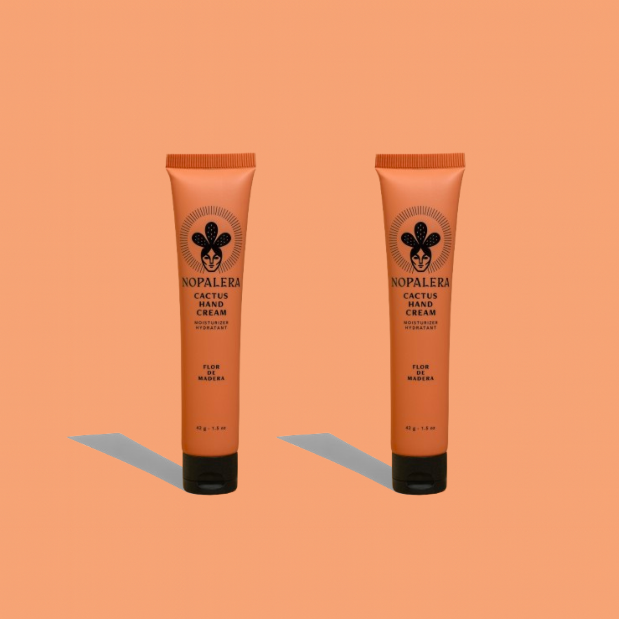Two Nopalera cactus hand cream tubes in Flor de Madera scent on a peach background.