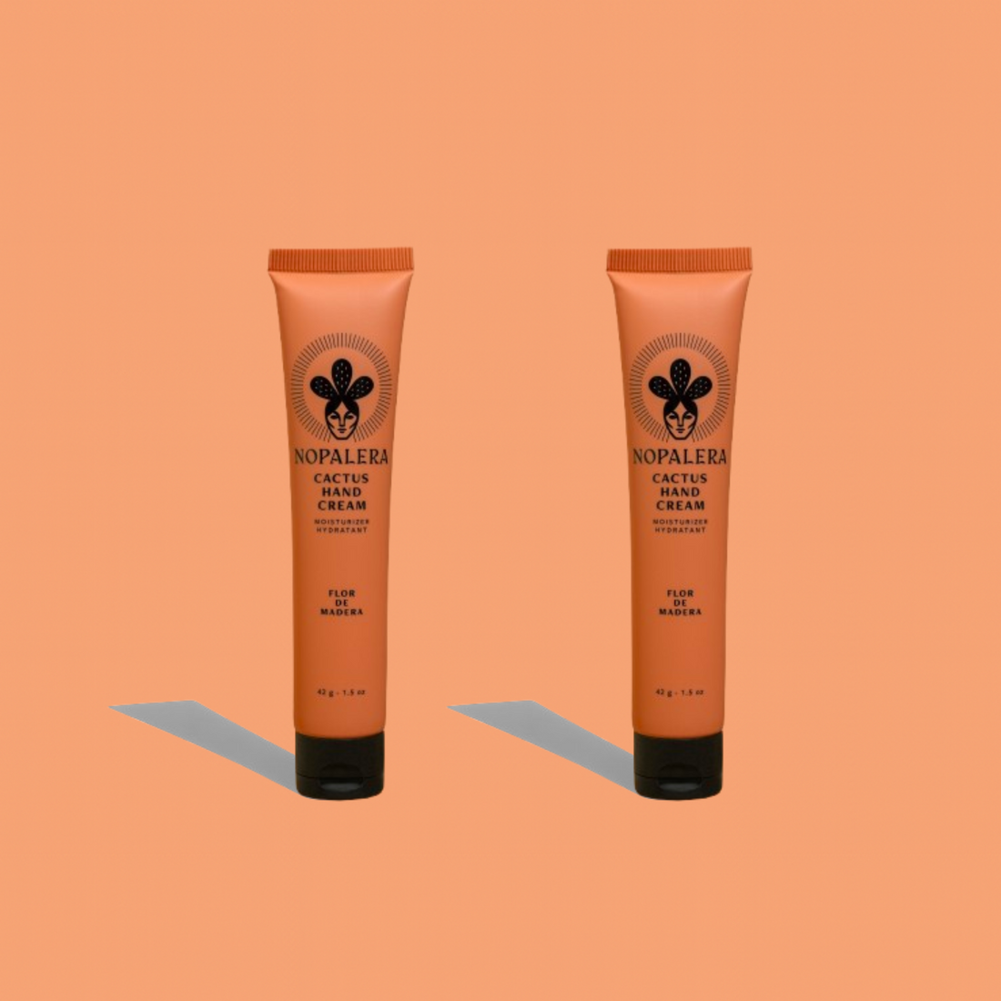 Two Nopalera cactus hand cream tubes in Flor de Madera scent on a peach background.