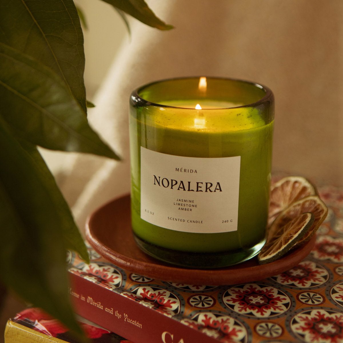 Nopalera Mérida scented candle in green glass jar lit on decorative tray