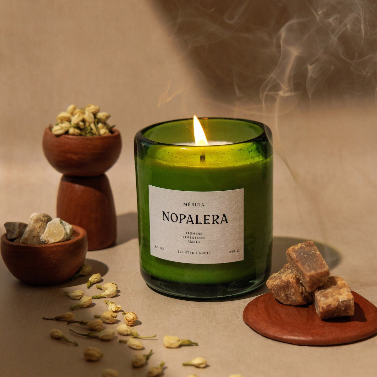 lit Nopalera Mérida scented candle in green glass jar with incense smoke and resin