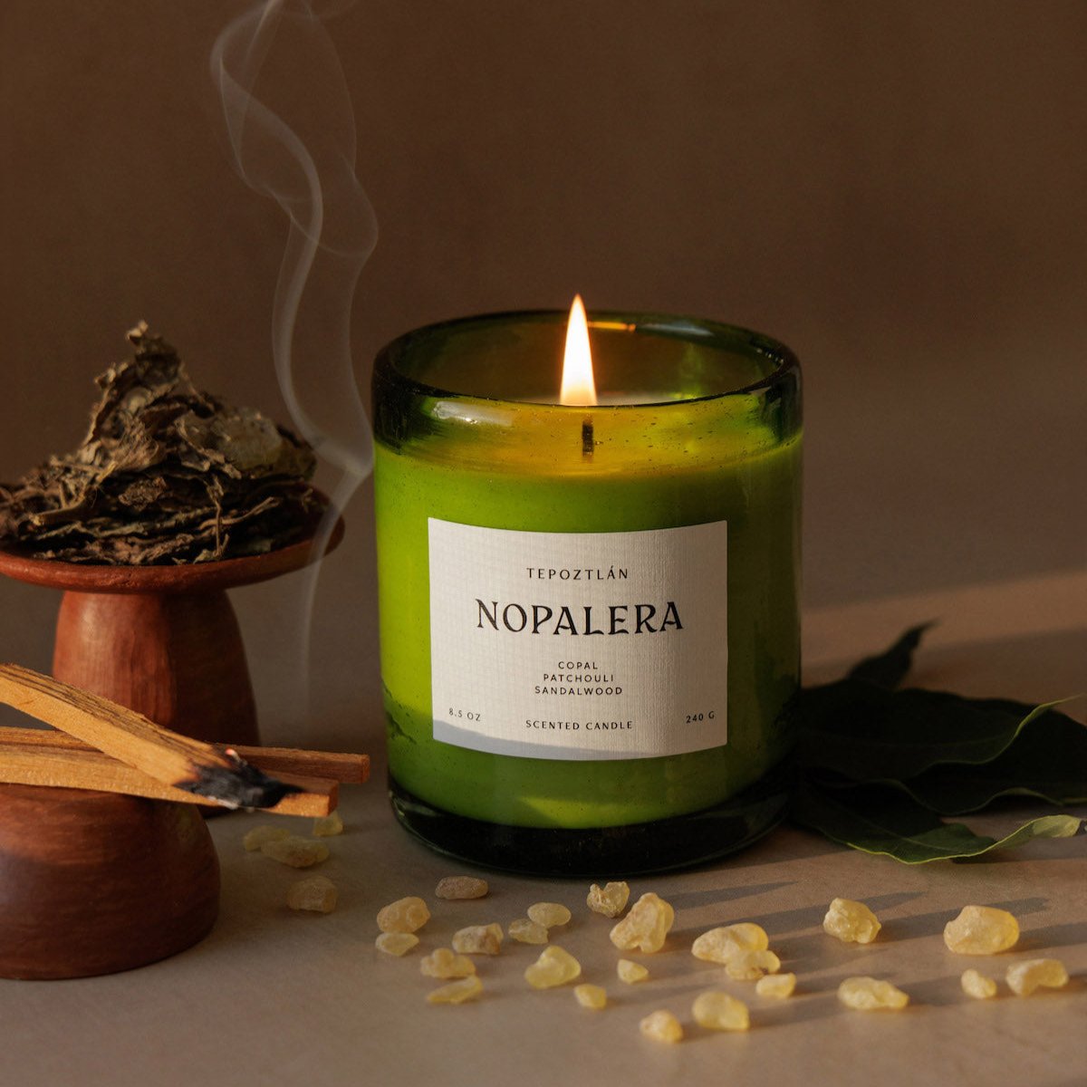 Nopalera scented Tepoztlan candle in green glass jar lit with incense beside it