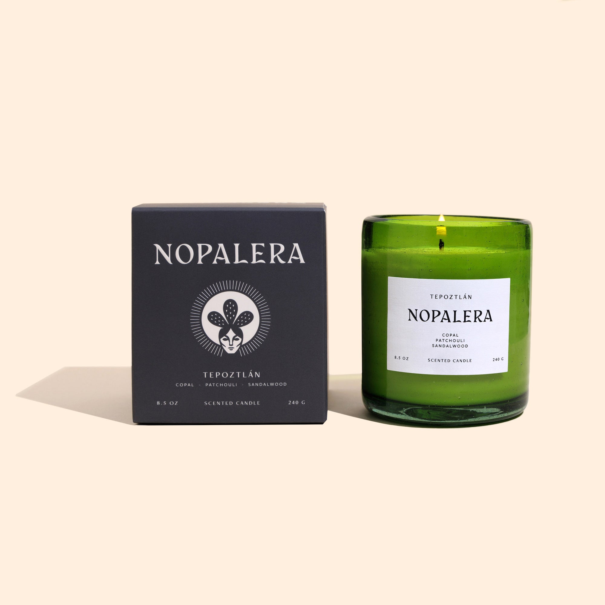 A green glass topoztlan candle with a white label that reads 'Nopalera' next to its black packaging box with the same brand name.