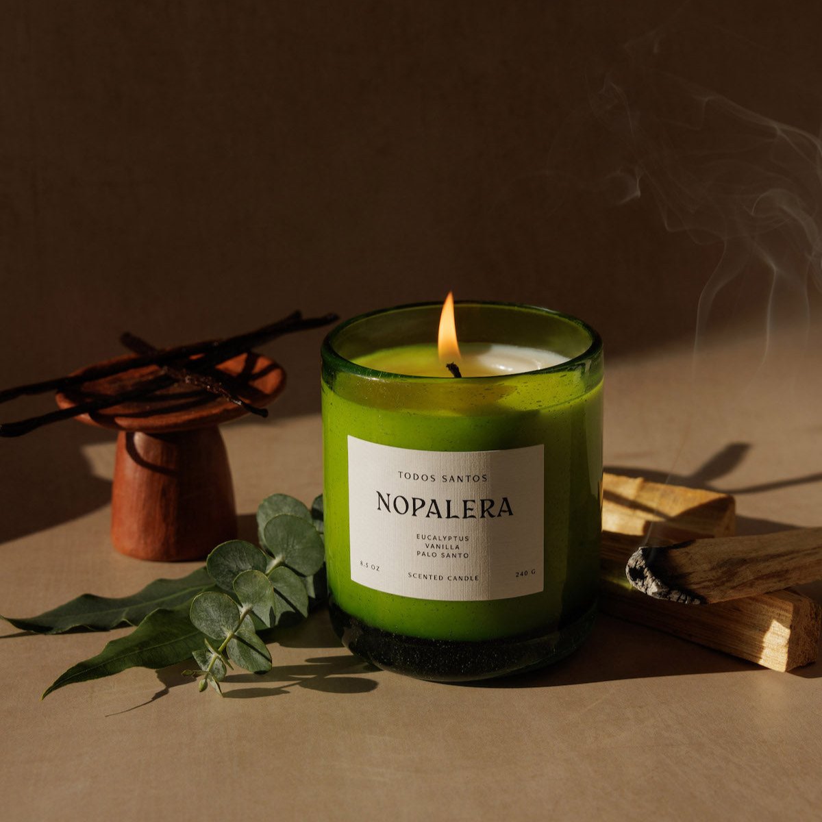 Nopalera Todos Santos scented candle in green glass jar lit with incense smoke