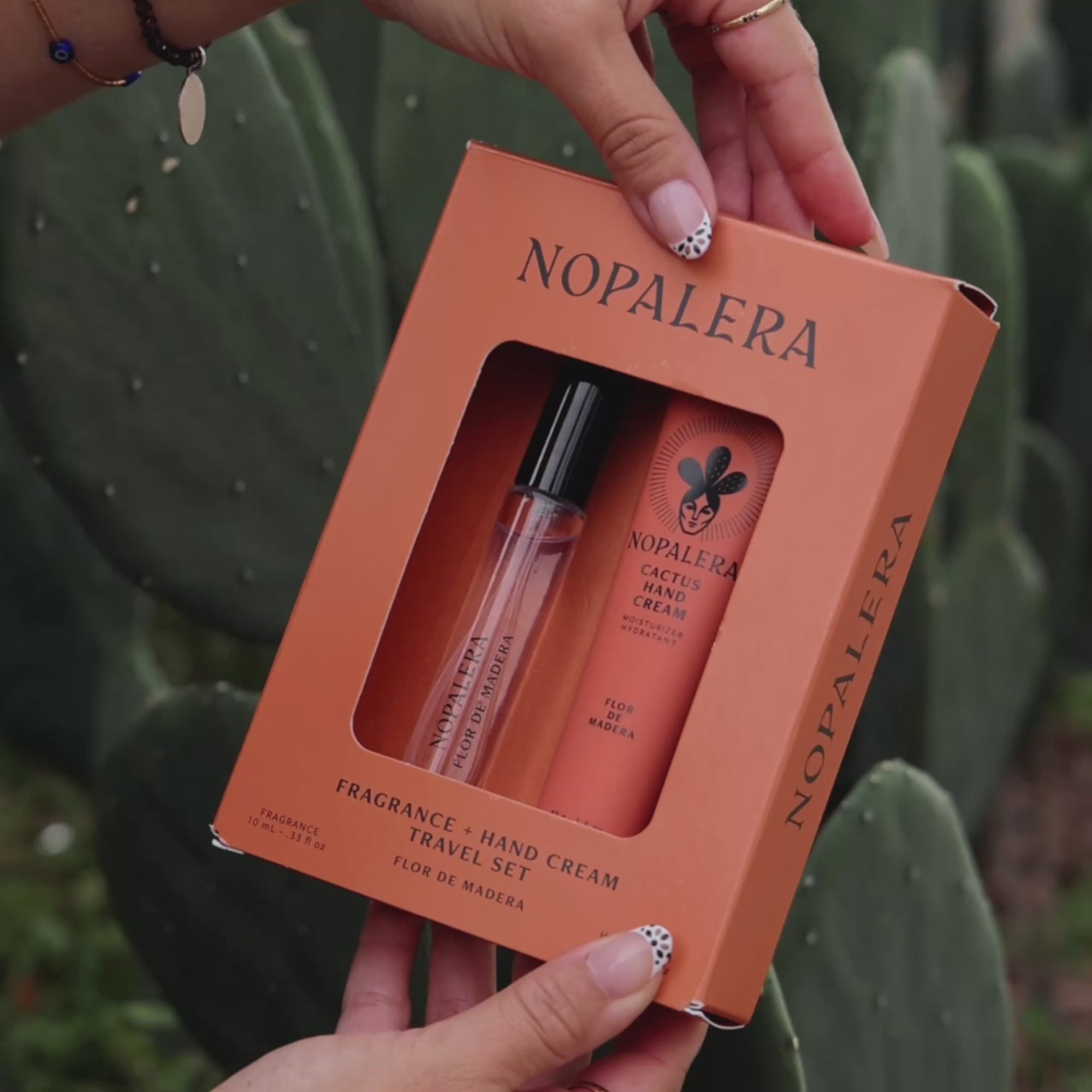 Person applying Nopalera cactus hand cream moisturizer in Flor de Madera scent with cactus plants in the background